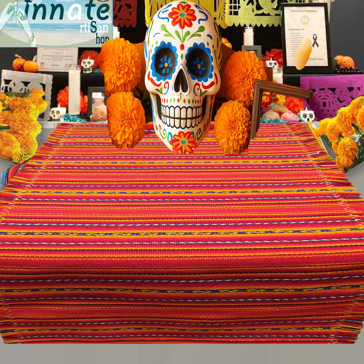Decorative skull with colorful flowers on a striped tablecloth with Halloween decorations in the background.