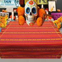Decorative skull with colorful flowers on a striped tablecloth with Halloween decorations in the background.