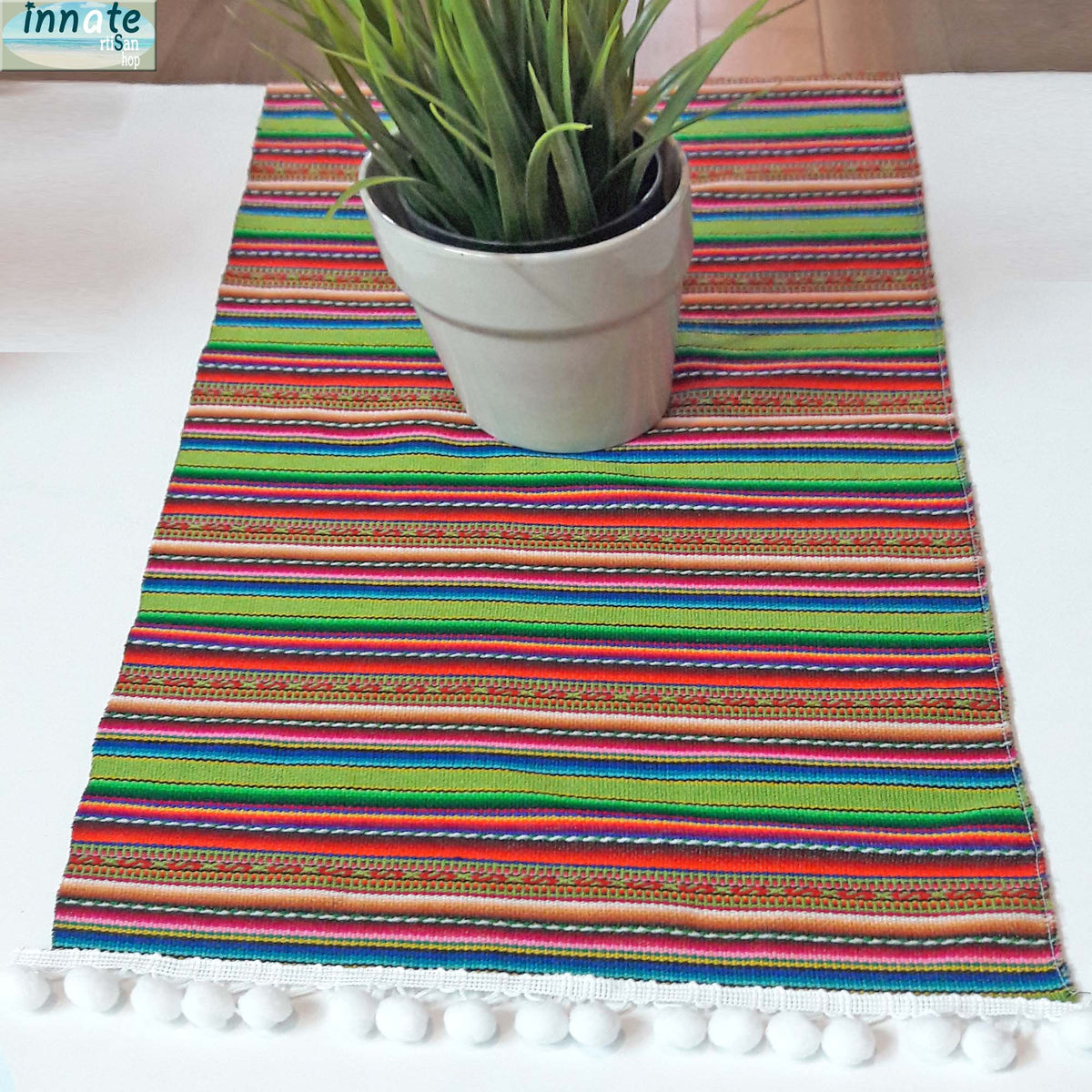 Colorful striped table runner with a potted plant on a white surface
