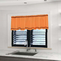 Orange curtain valance on a window in a kitchen with a sink.