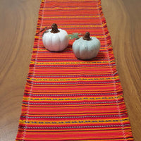 Colorful striped table runner with two small pumpkins on a wooden surface