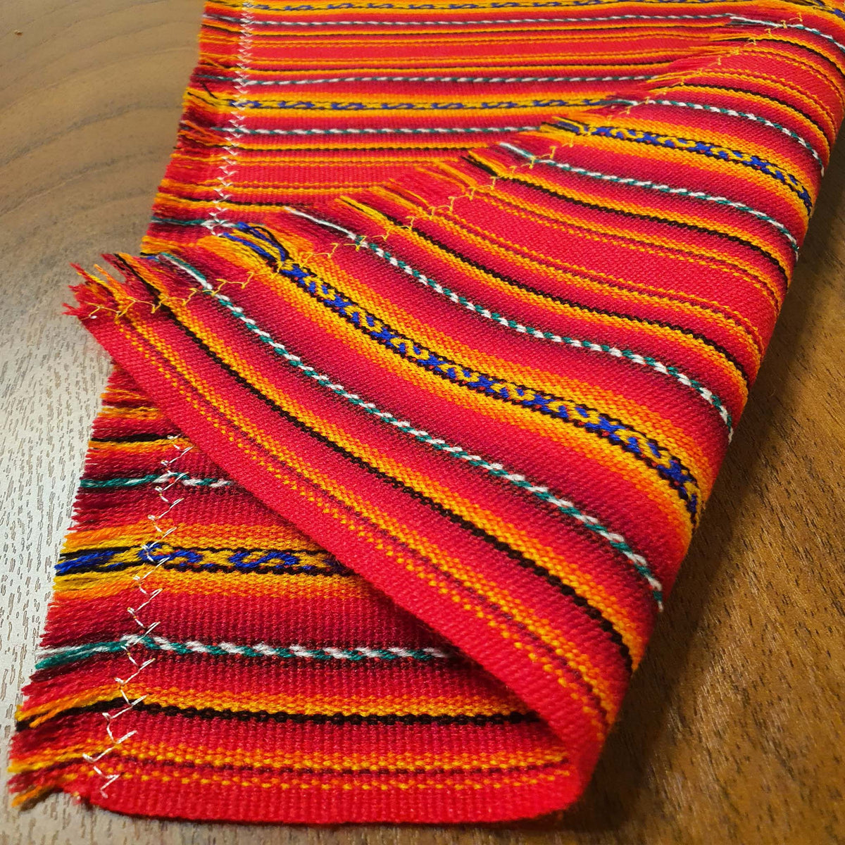 Stack of colorful woven fabric on a wooden surface