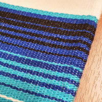 White serape on table, table runner, white and blue, artisan, close up of the woven