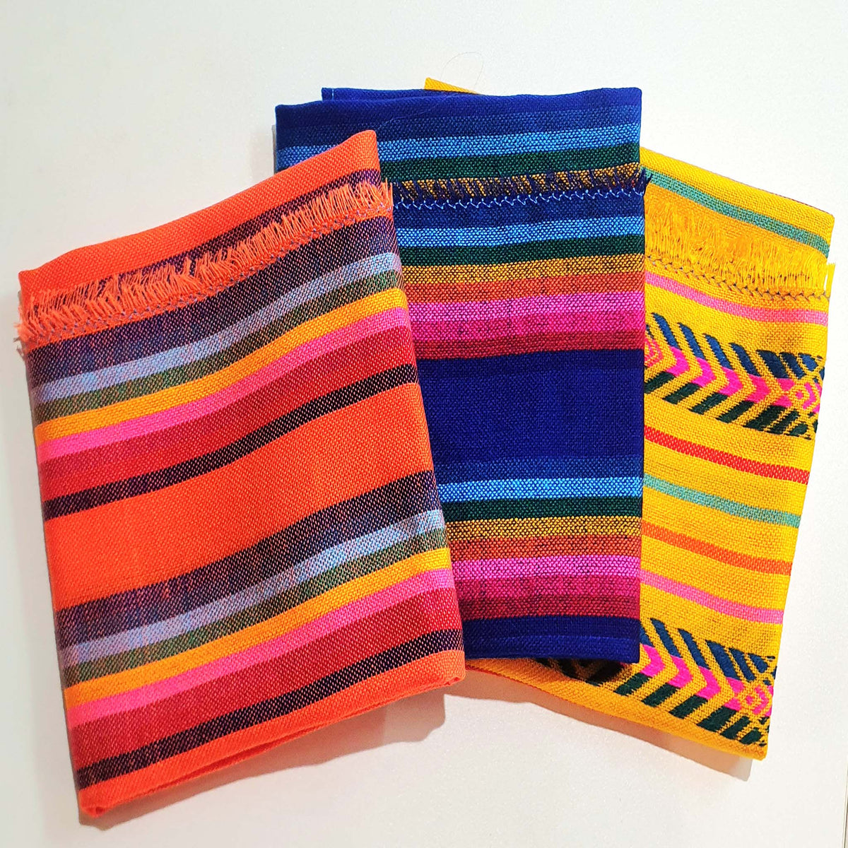 Three colorful fabric blankets with striped and patterned designs, baby blankets